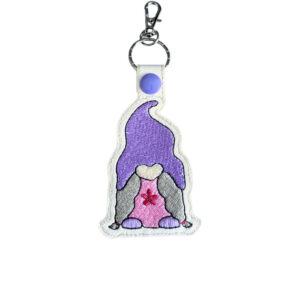 Embroidered girl gnome keyring in faux leather, featuring a purple hat, pink dress, grey hair and sturdy metal keyring hardware.