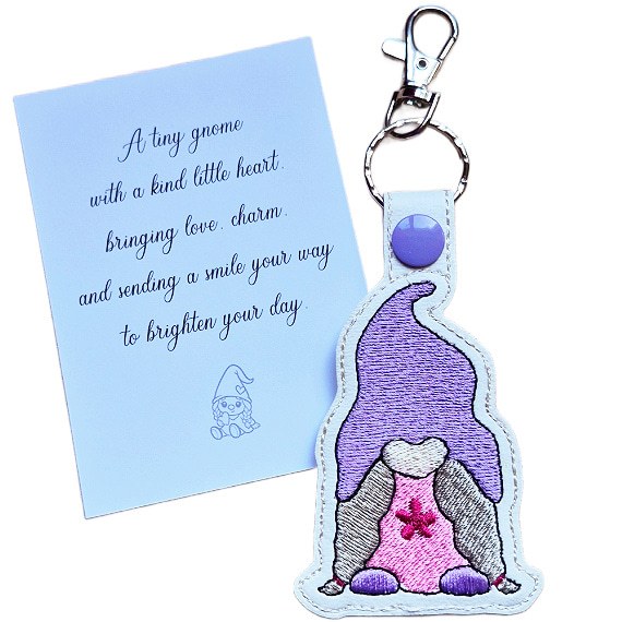 Embroidered girl gnome keyring with a purple hat and pink dress, shown beside a matching keepsake card with a kind-hearted gnome gift message.