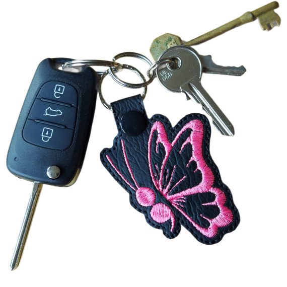 Black faux leather butterfly keyring attached to a set of keys, showing its size and everyday use.