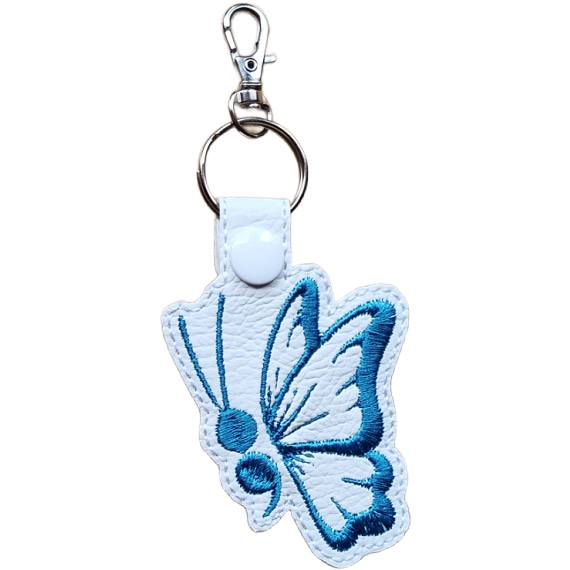 White faux leather butterfly keyring with blue embroidered wing detail, white snap and silver metal clasp.