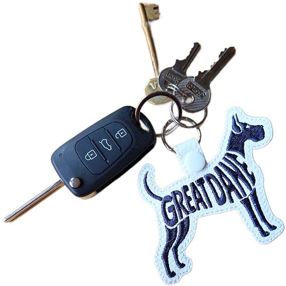White embroidered Great Dane word art keyring attached to a set of keys, showing how it looks in everyday use.