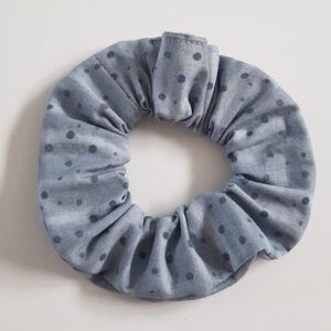 A pale grey scrunchie with darker grey small spots pictured on a white background