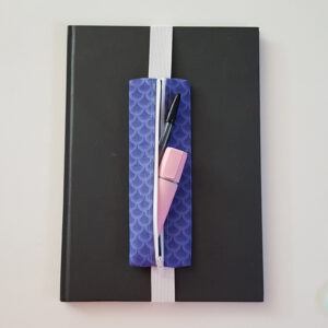 Handmade A4 planner zipper pouch in blue mermaid scale print cotton fabric, shown fitted around a black A4 notebook with a white zip and white elastic strap, holding pens and stationery items.