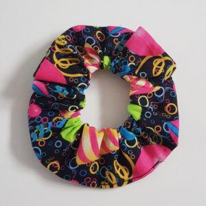 Handmade birthday scrunchie with colourful party icons on black fabric.
