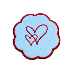 Embroidered heart candle coaster with a red stitched heart design in the centre, soft textured background and rich red scalloped border.