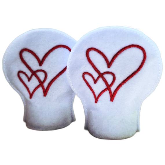 Two unlit heart tealight covers made from white felt, each embroidered with flowing red heart designs.