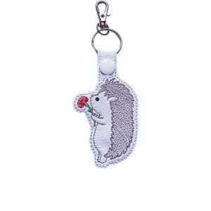 Embroidered hedgehog keyring in faux leather, featuring a cute hedgehog holding a flower with sturdy metal keyring hardware.
