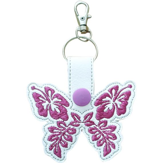 White faux leather hibiscus butterfly keyring with pink floral embroidered wings, lilac snap and silver metal clasp.