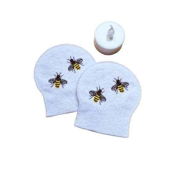 Embroidered honey bee tealight covers on white felt with stitched bees and honeycomb detail, shown beside a battery operated LED tealight.