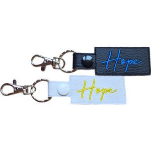 Embroidered Hope keyring in faux leather, with the word 'Hope' stitched on black and white backgrounds with sturdy metal hardware.