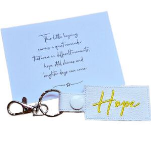 Embroidered Hope keyring in white faux leather, shown beside a matching keepsake card with an encouraging message about hope and brighter days.