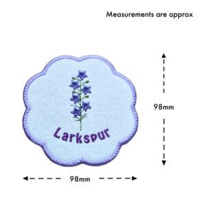 July birth flower candle coaster size guide showing the embroidered larkspur design with stitched text and scalloped purple border, measuring approximately 98mm x 98mm.