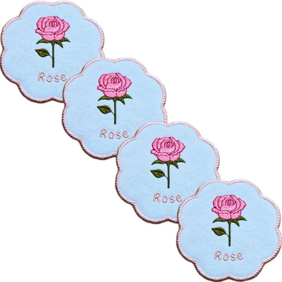 Set of four embroidered June birth flower candle coasters, each with a pink rose, green leaves, stitched rose text and a softly scalloped pink border.