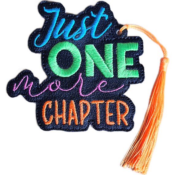 Embroidered 'Just One More Chapter' bookmark on black faux leather with bright blue, green, pink and orange stitched wording and a coordinating tassel.