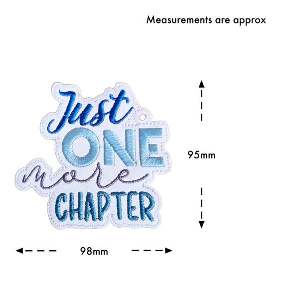Embroidered 'Just One More Chapter' bookmark on white faux leather size guide showing approximate measurements of 95mm high x 98mm wide.