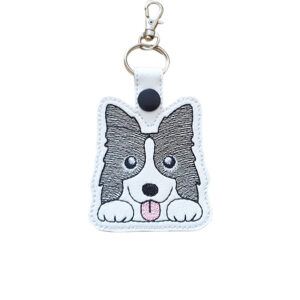 Kawaii Border Collie keyring made from white faux leather, with embroidered ears, paws, pink tongue and silver metal hardware.