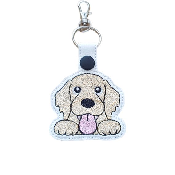 Kawaii Golden Retriever keyring made from white faux leather, with embroidered floppy ears, sweet paws, pink tongue and silver metal hardware.