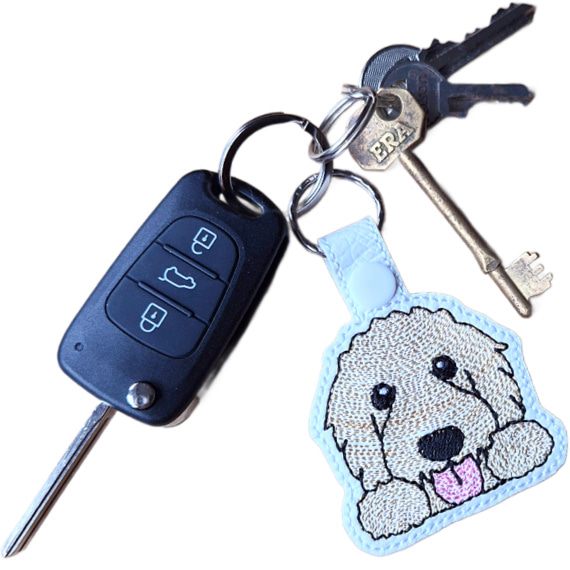 Kawaii Goldendoodle keyring attached to a set of keys, showing the embroidered dog design in everyday use.