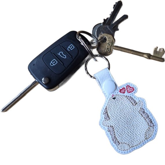 Embroidered Kawaii Hedgehugs keyring attached to a set of keys, featuring a cute hedgehog with two red hearts and sturdy metal hardware.