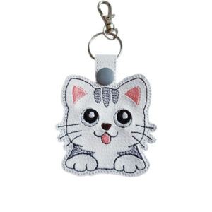 White faux leather kawaii kitty cat keyring with embroidered grey tabby details, big eyes, pink tongue and silver metal clasp.