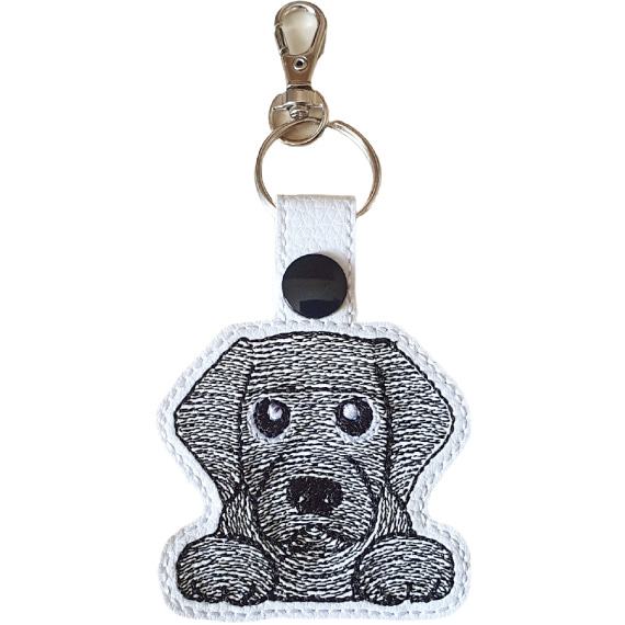 Kawaii Black Labrador keyring made from white faux leather, with embroidered floppy ears, sweet paws and metal hardware.