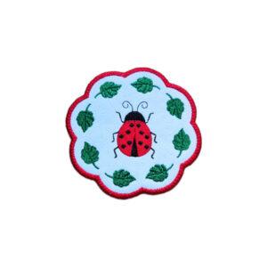 Embroidered ladybird candle coaster with a bright stitched ladybird in the centre, green leaf details and scalloped edging.