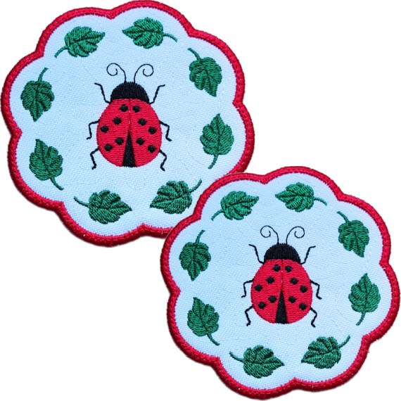 Set of two embroidered ladybird candle coasters with bright stitched ladybirds, green leaf details and red scalloped edging.