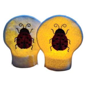 Lit ladybird tealight covers glowing warmly over LED tealights, showing embroidered ladybirds on soft felt for a cheerful garden inspired display.
