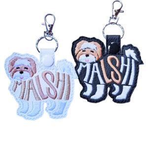 Embroidered Malshi word art keyrings in black and white faux leather, shown with metal split rings and lobster clasps.