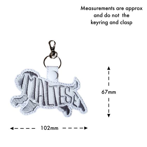 White Maltese word art keyring with size guide showing the embroidered dog design measures approximately 67mm x 102mm, excluding the keyring and lobster clasp.