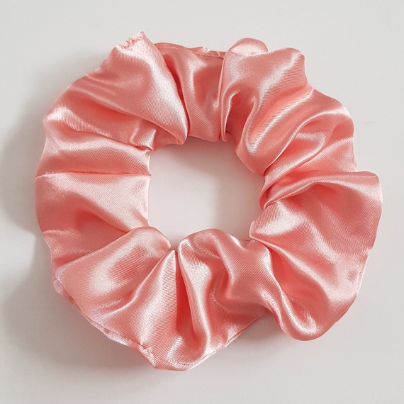 Pale pink satin scrunchie with a soft sheen on a white background.