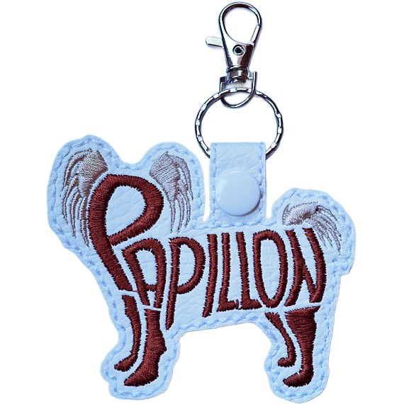 White embroidered Papillon word art keyring made from faux leather, with stitched breed lettering and silver metal hardware.
