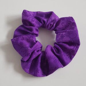 Purple cotton scrunchie with a subtle floral pattern on a white background.