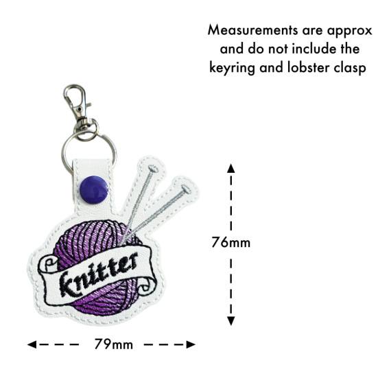 Size guide for a white faux leather knitting keyring embroidered with a purple yarn ball, silver knitting needles and 'Knitter' banner, measuring approximately 79mm by 76mm.