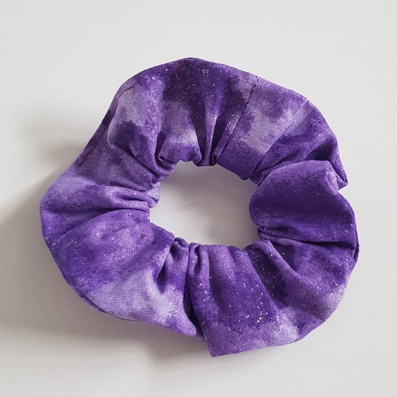 Handmade purple glitter cotton scrunchie on a white background.