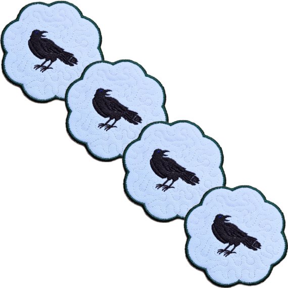 Set of four embroidered raven candle coasters with matching black raven designs, scalloped edging and subtle gothic background detail.