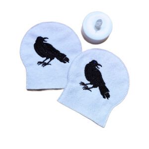 Set of two embroidered raven tealight covers made from soft felt, shown with an LED tealight for a moody gothic inspired display.