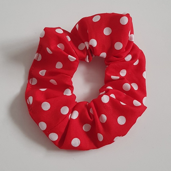 Red cotton scrunchie with white polka dots on a light background.