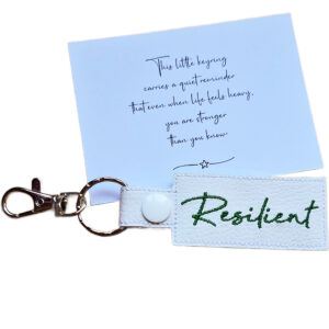 Embroidered Resilient keyring in white faux leather, shown beside a matching keepsake card with an encouraging message about strength.
