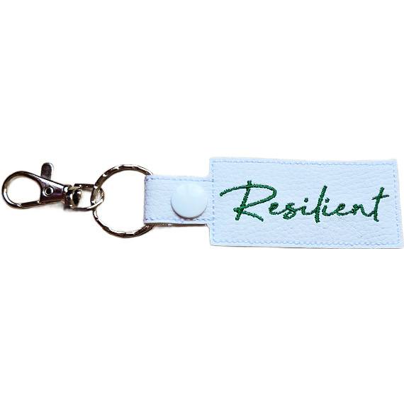 Embroidered Resilient keyring in white faux leather, with the word 'Resilient' stitched in green and sturdy metal keyring hardware.