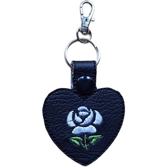 Black faux leather heart keyring with a white embroidered rose design, black snap fastening and silver lobster clasp hardware.