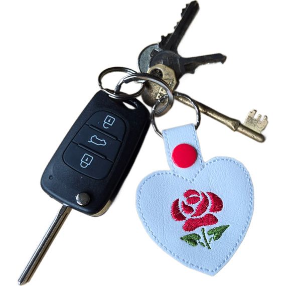 White faux leather rose heart keyring with red embroidered rose and snap fastening, shown attached to a set of keys with silver keyring hardware.
