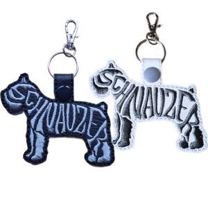 Embroidered Schnauzer word art keyrings in black and white faux leather, shown with metal split rings and lobster clasps.