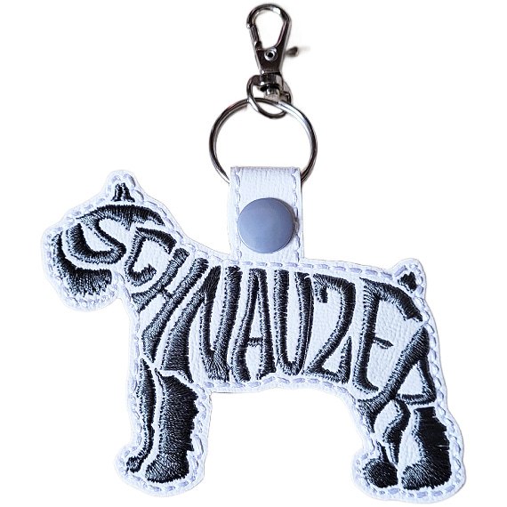 White embroidered Schnauzer word art keyring made from faux leather, with stitched breed lettering and silver metal hardware.