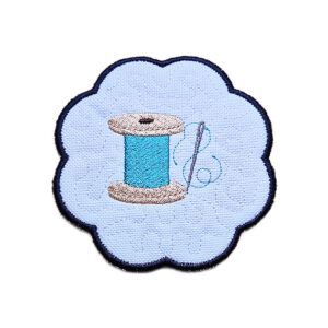 Embroidered sewing candle coaster with a stitched thread spool design, scalloped edging and soft craft room style detailing.