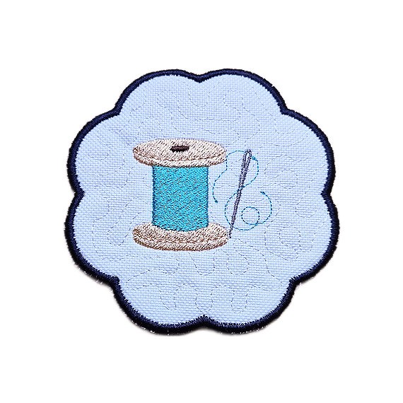 Embroidered sewing candle coaster with a stitched thread spool design, scalloped edging and soft craft room style detailing.