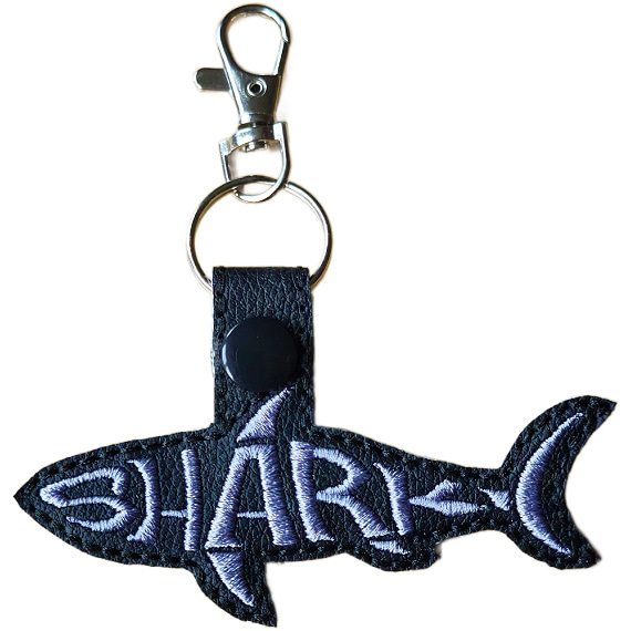 Black faux leather shark word art keyring with grey embroidered 'Shark' lettering, black snap fastening and silver lobster clasp hardware.