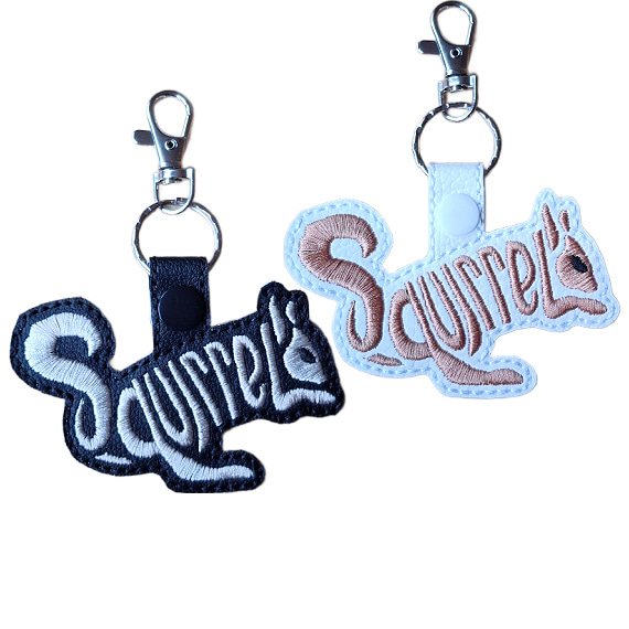 Black and white faux leather squirrel word art keyrings with embroidered 'Squirrel' lettering, snap fastenings and silver lobster clasp hardware.