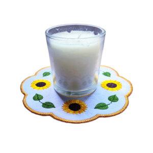 Embroidered sunflower candle mat with yellow sunflowers, green leaves and a golden scalloped border, shown with a glass candle in the centre.