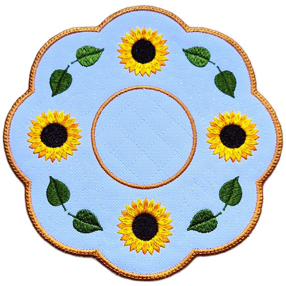 Close up of an embroidered sunflower candle mat with yellow sunflowers, green leaves, circular centre and warm golden scalloped border.
